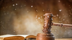 Wooden gavel with open law book and splashing water on table.